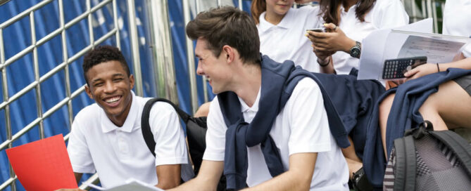 teenage school children siting and laughing together