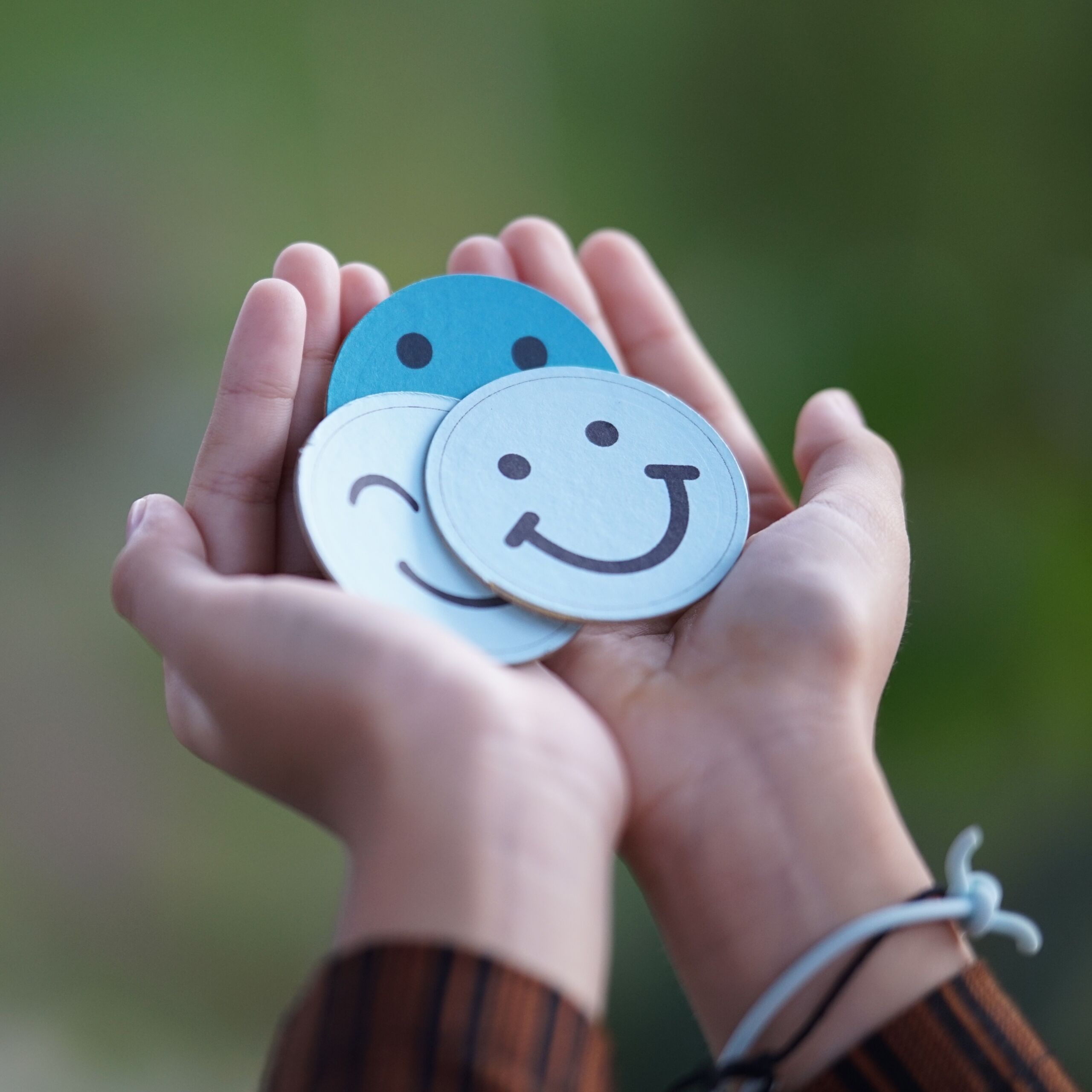 Hands holding emoji faces